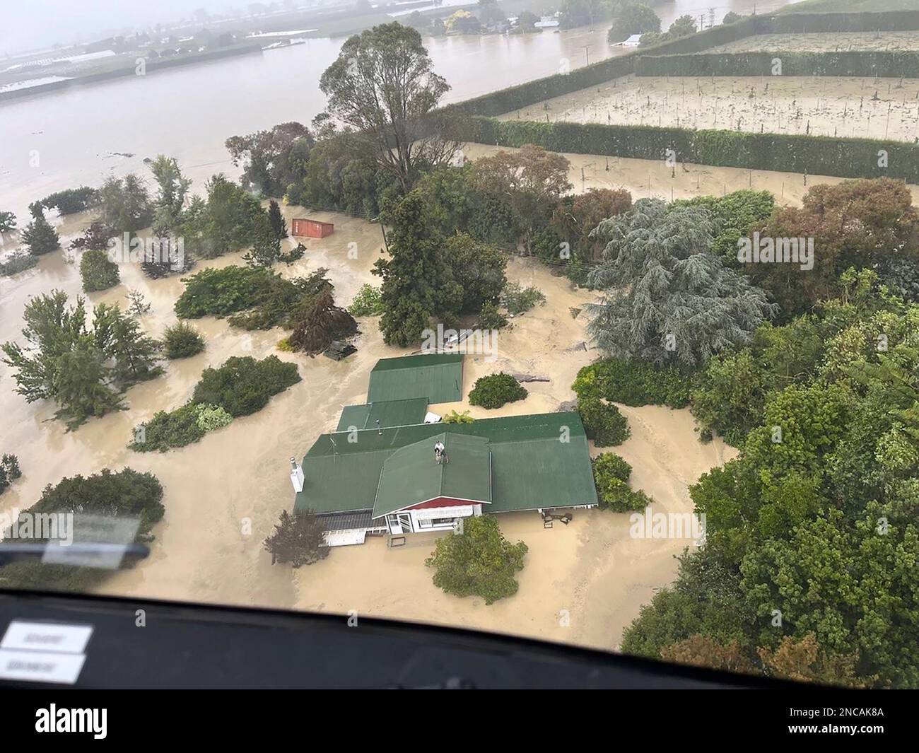 In this image released by the New Zealand Defense Force on Wednesday, Feb. 15, 2023, people stand on a rooftop of a home waiting to be winched to safety by helicopter in the Esk Valley, near Napier, New Zealand. The New Zealand government declared a national state of emergency Tuesday after Cyclone Gabrielle battered the country's north in what officials described as the nation's most severe weather event in years. (New Zealand Defense Force via AP) Stock Photo