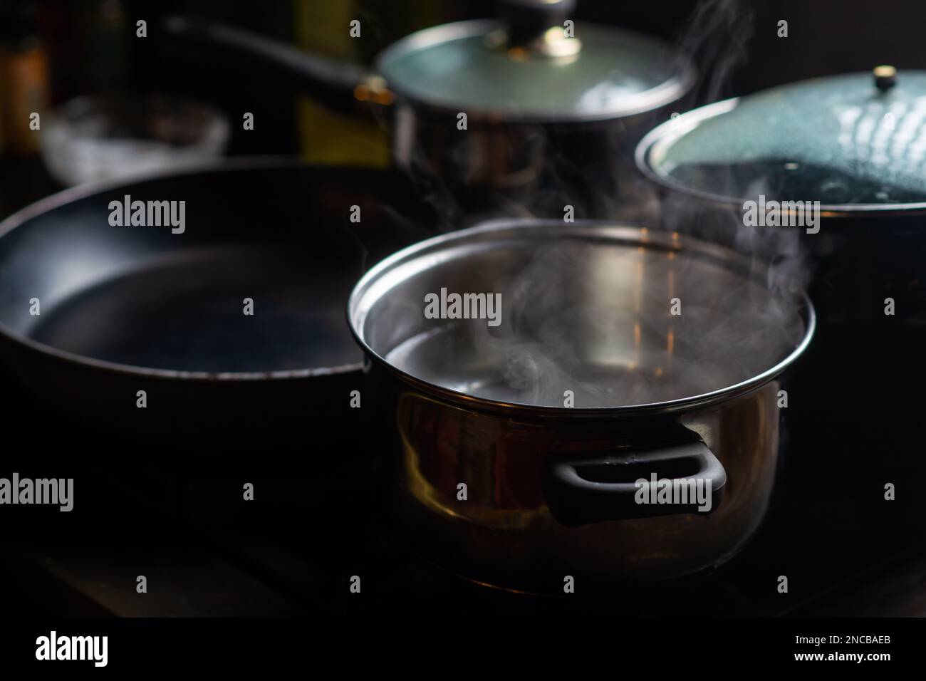 A pot of boiling water on a kitchen stove. Kitchen utensils are nearby