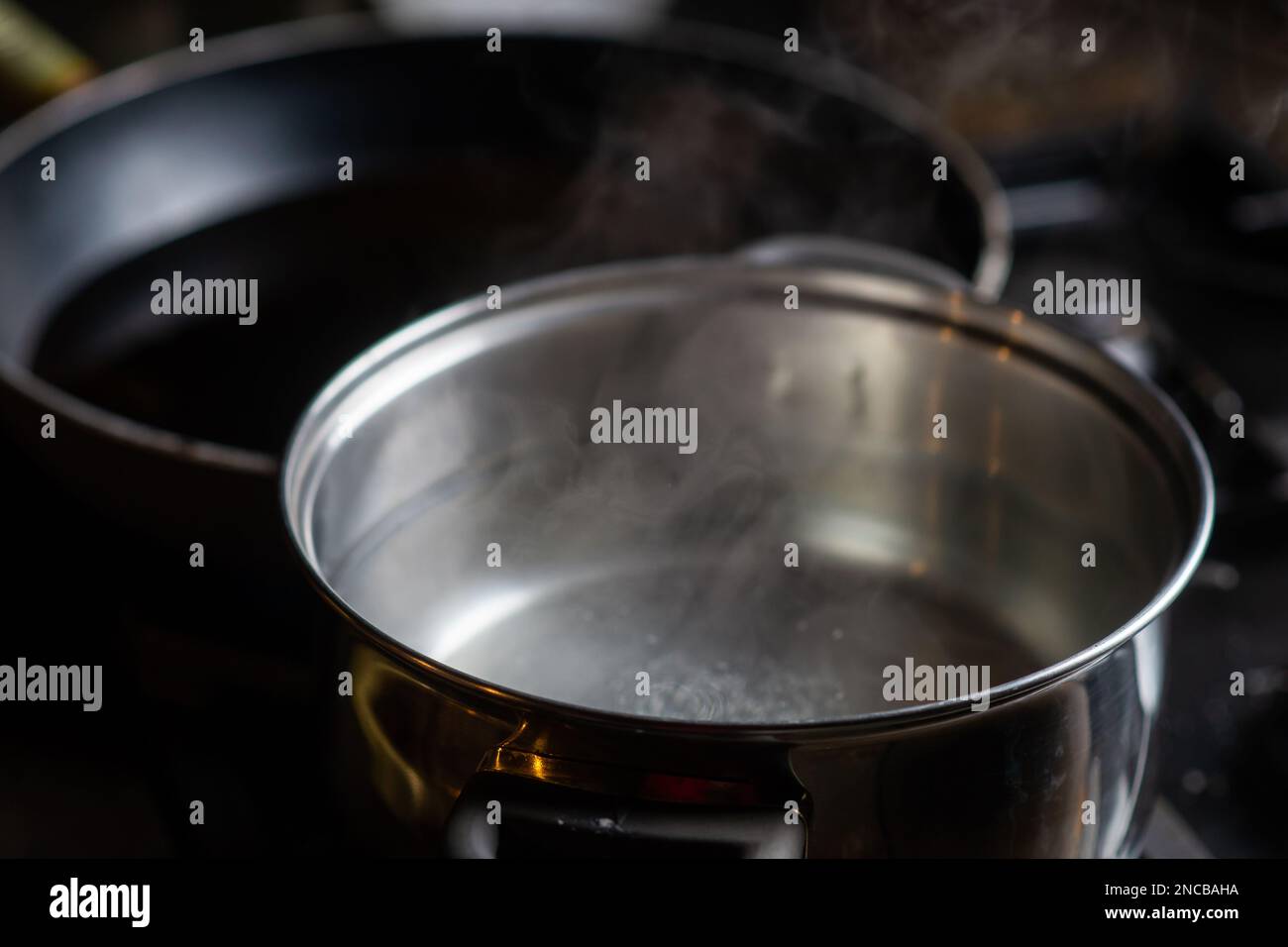 https://c8.alamy.com/comp/2NCBAHA/a-pot-of-boiling-water-on-a-kitchen-stove-kitchen-utensils-are-nearby-2NCBAHA.jpg