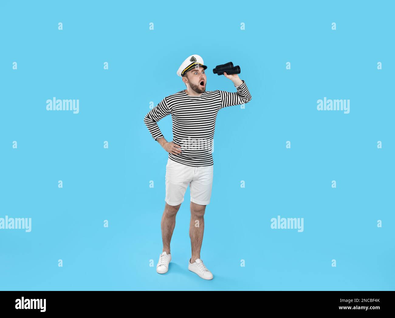 Shocked sailor with binoculars on light blue background Stock Photo