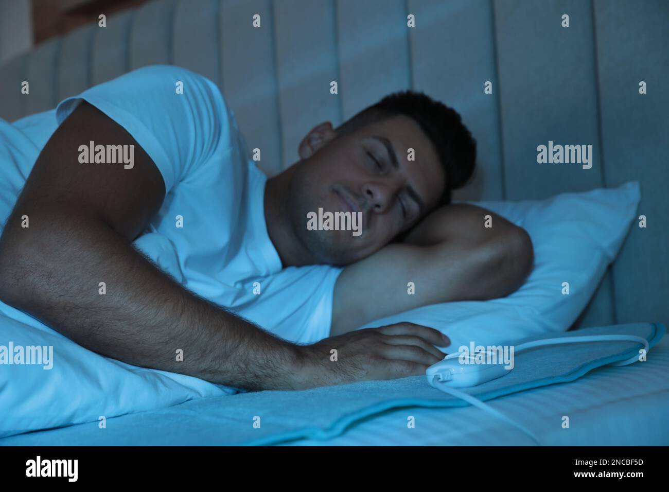 Man sleeping on electric heating pad in bed at night Stock Photo Alamy