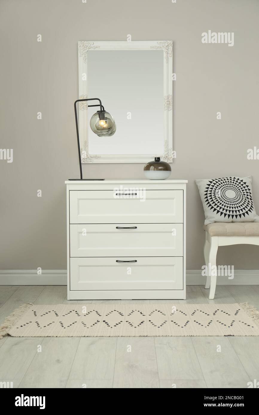 Hallway with stylish chest of drawers and mirror. Interior design Stock