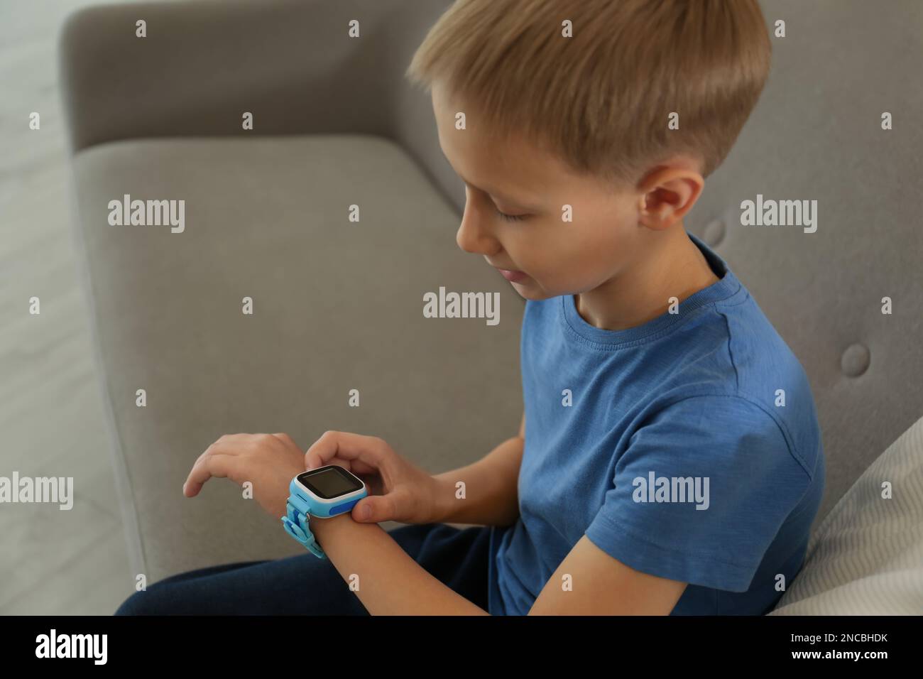 Boy with stylish smart watch on sofa Stock Photo