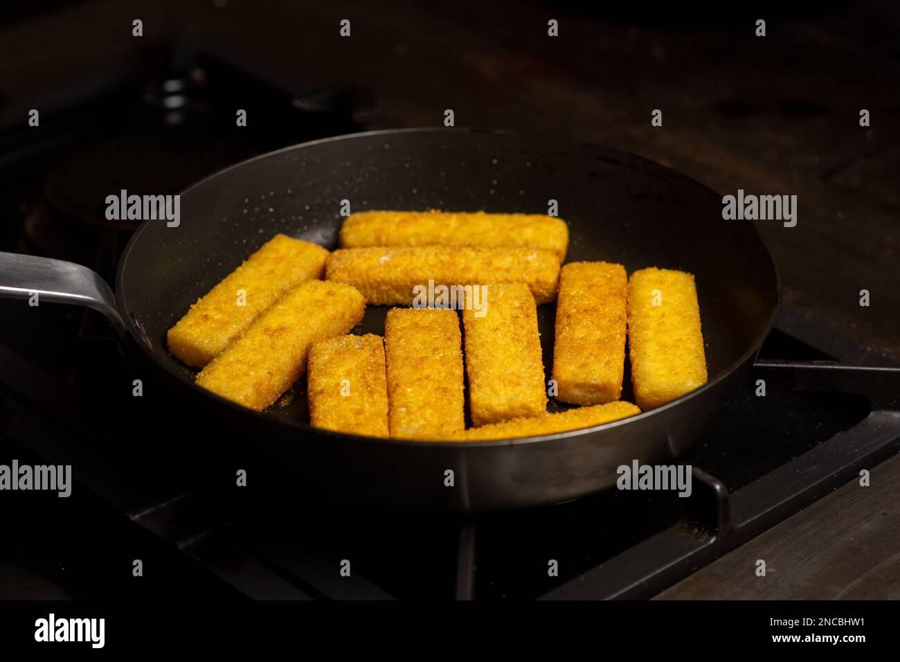 Fish sticks in a pan. Preparation of frozen fish sticks. Fast food