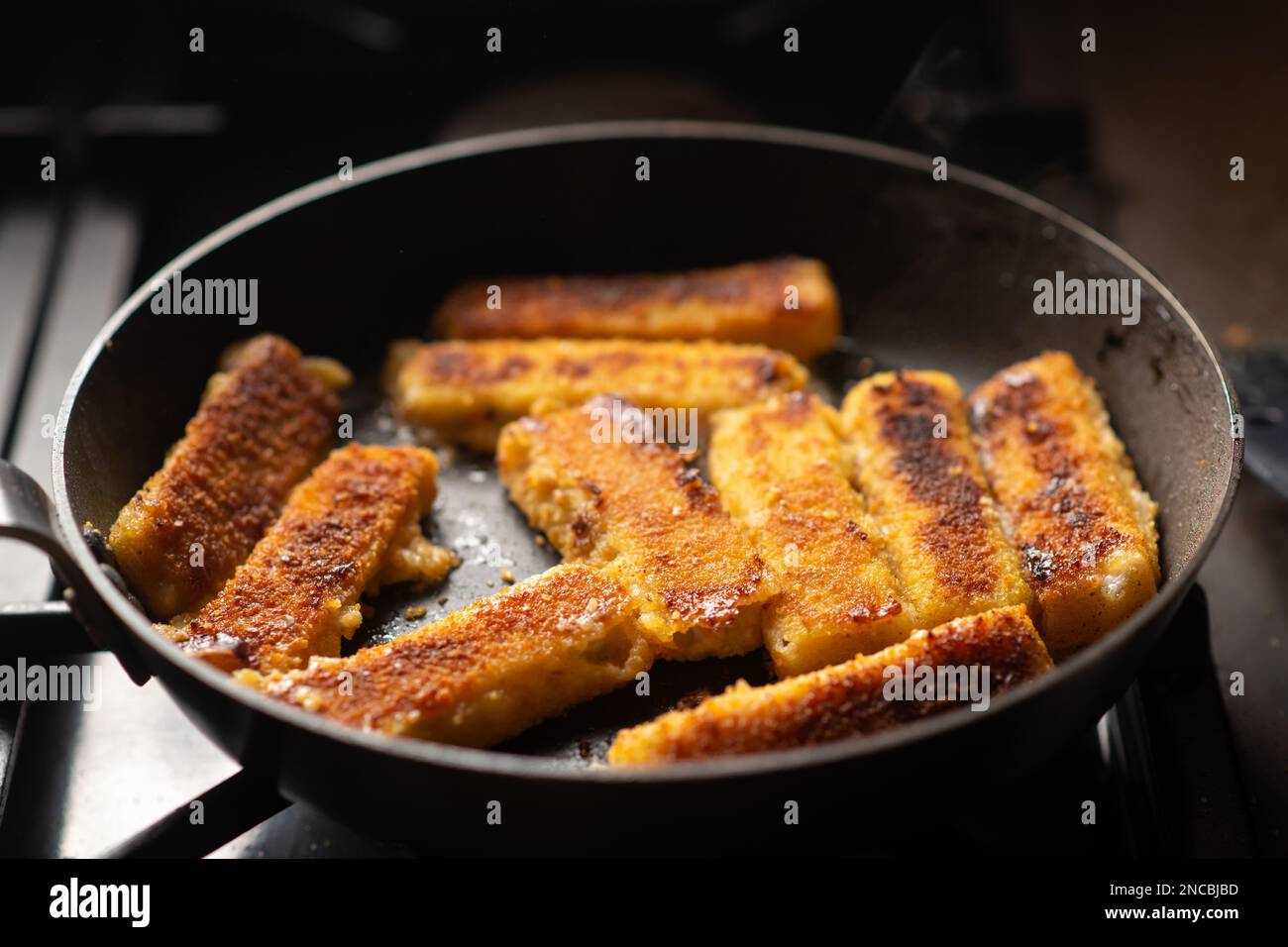 Fried fish sticks breaded in a frying pan. Preparation of frozen fish