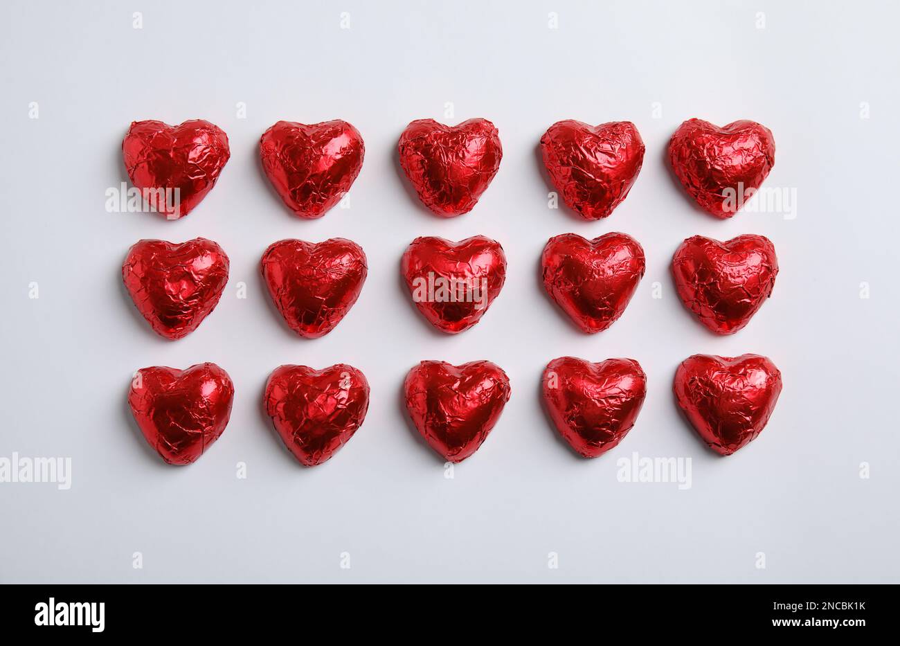 Heart shaped chocolate candies on white background, flat lay. Valentine