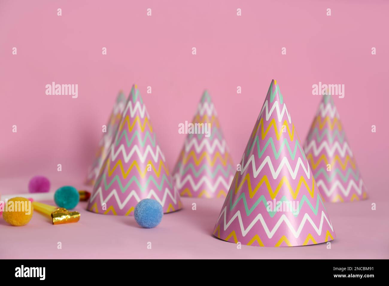 Colorful party hats, blower and fluffy balls on pink background Stock ...