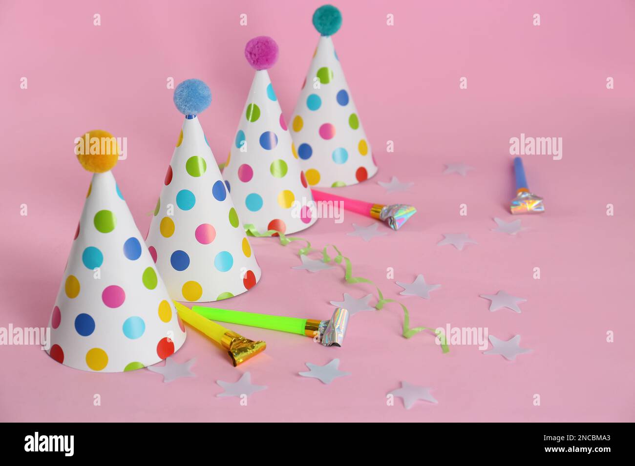Colorful party hats with fluffy balls and blowers on pink background ...