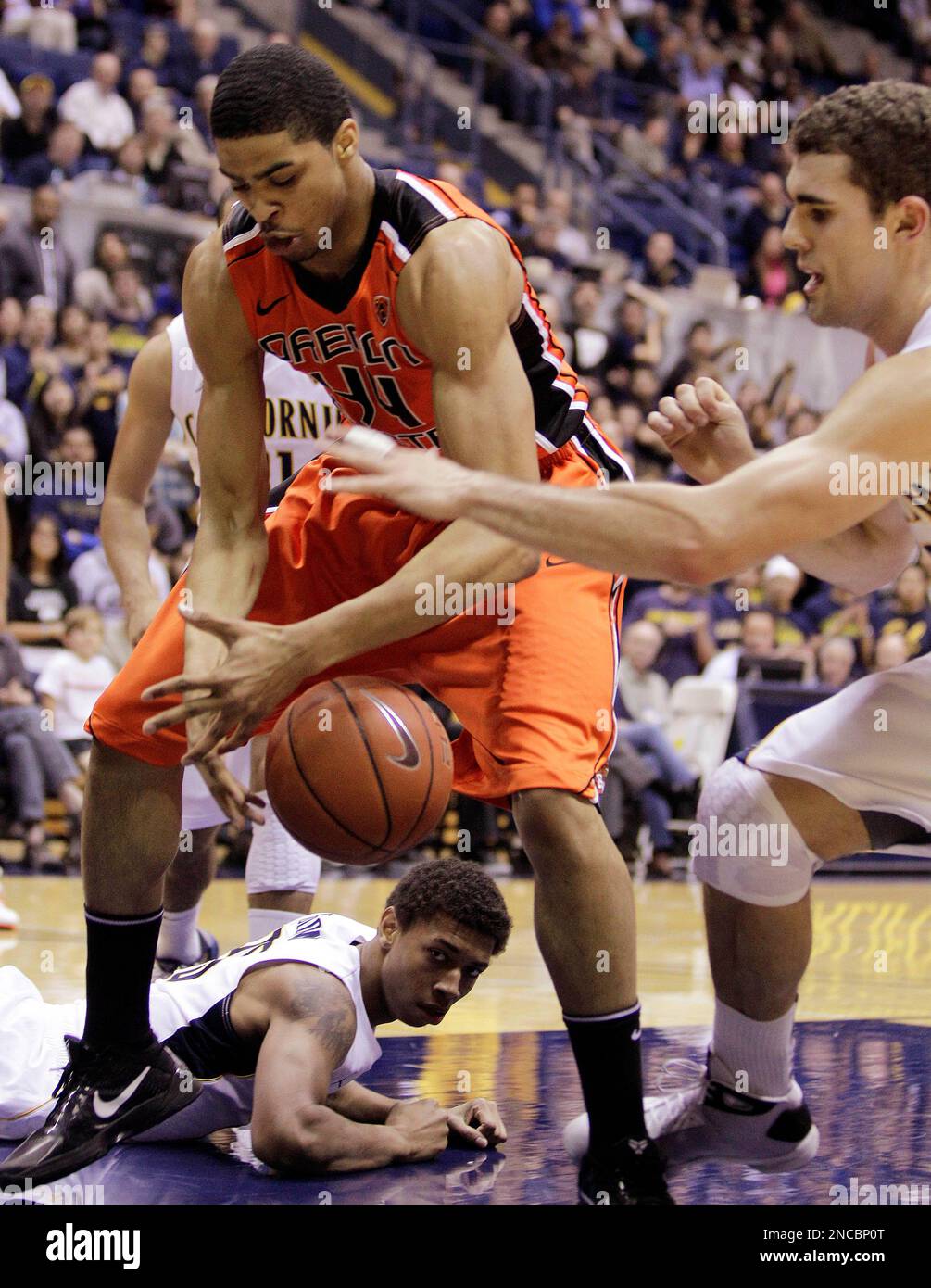 Oregon State's Devon Collier (44) and California's Harper Kamp, right,  fight for a loose ball as California's Richard Solomon watches from the  floor during the first half of an NCAA college basketball