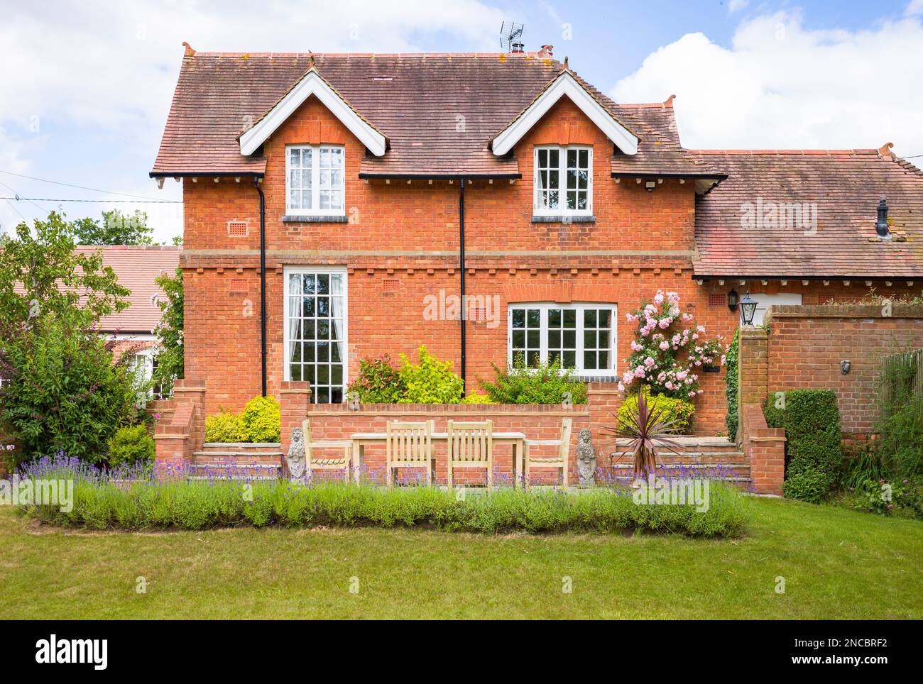 Large UK mansion house and garden with lawn and patio terrace with teak garden furniture Stock Photo