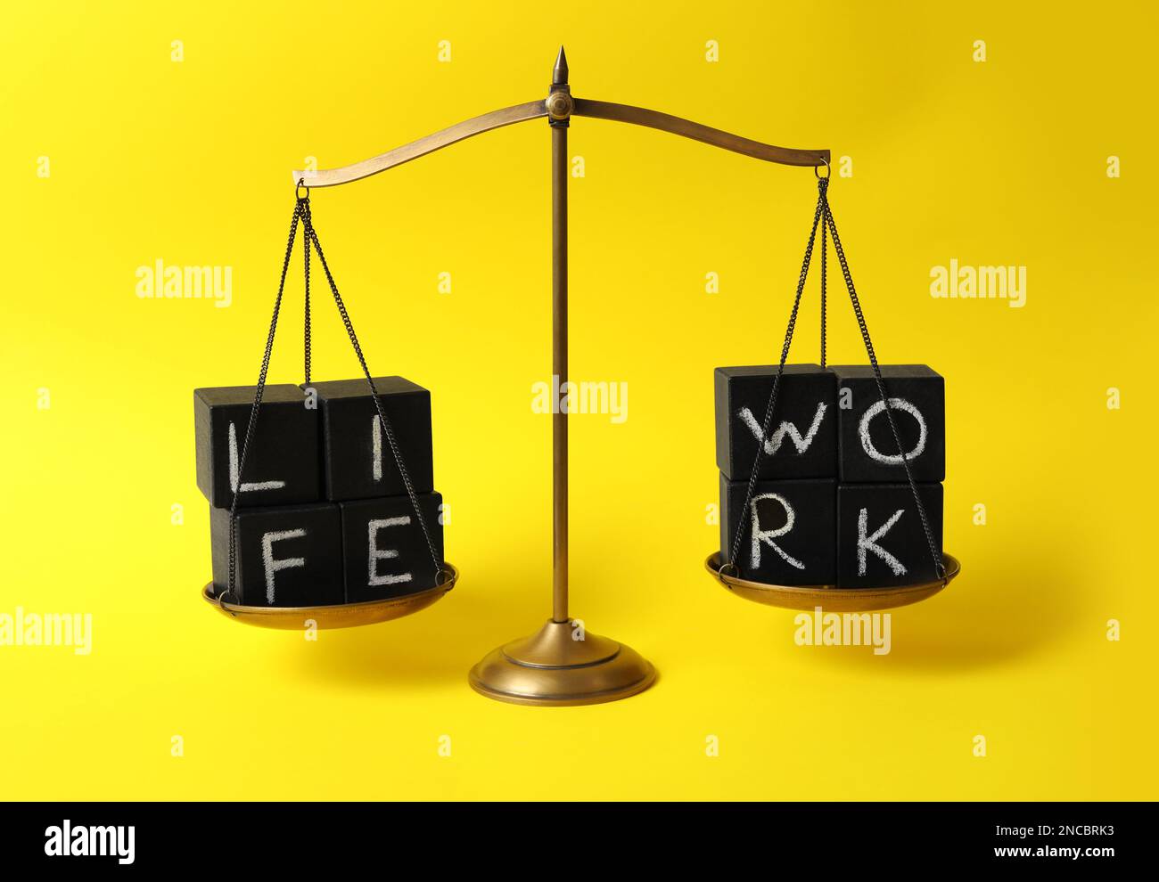 Words Life, Work made with black cubes on scales against yellow ...