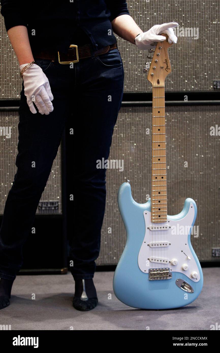 A Bonhams' employee poses with a Daphne Blue 2008 Fender Eric Clapton  Signature Stratocaster guitar on display at the auction house in London,  Friday, Jan. 21, 2011. The guitar used by Clapton
