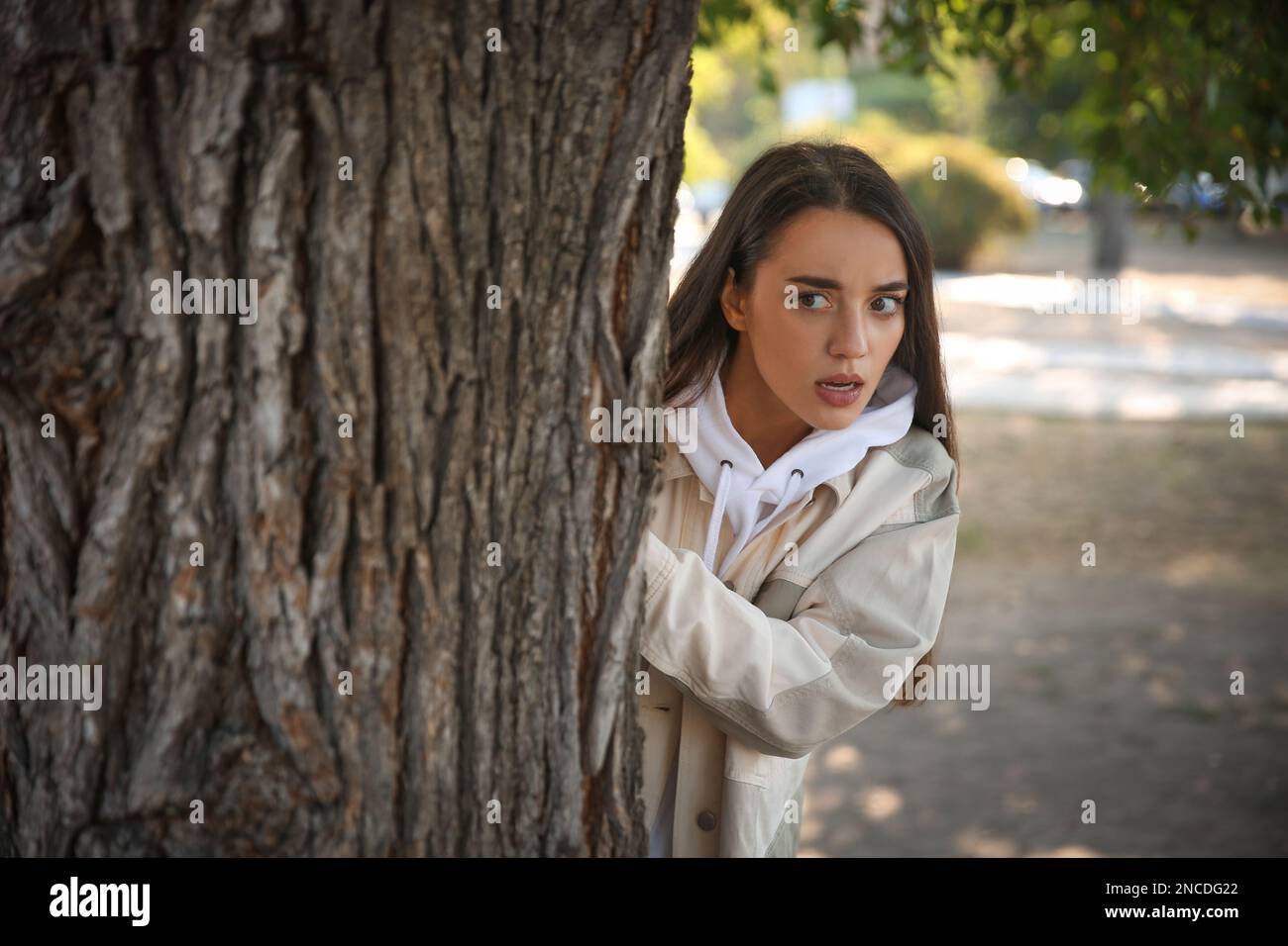 Jealous woman spying on ex boyfriend in park Stock Photo