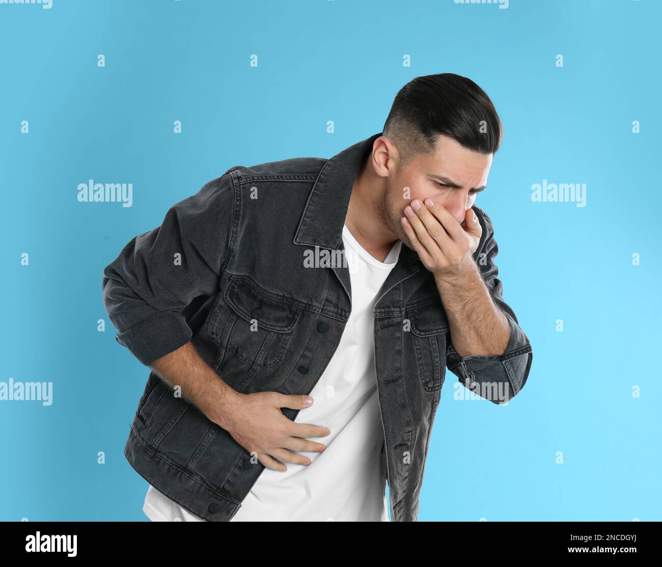 Man suffering from stomach ache and nausea on light blue background