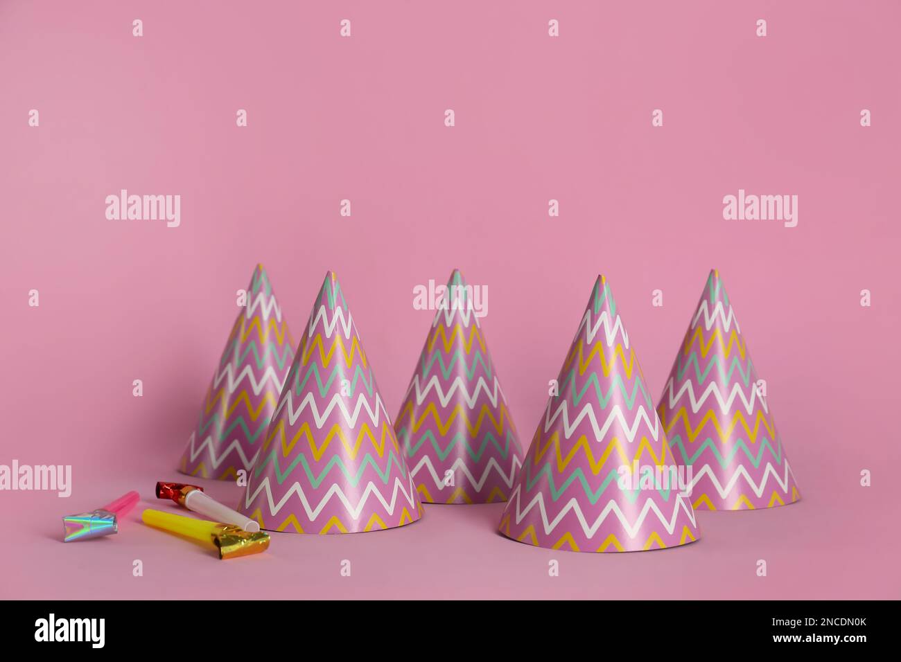 Colorful party hats and blowers on pink background Stock Photo - Alamy
