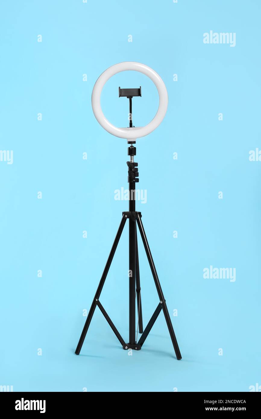 Modern tripod with ring light on blue background Stock Photo - Alamy