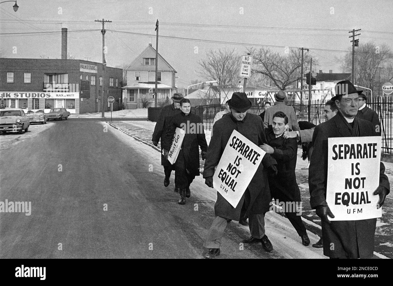 An unidentified man about to be restrained grabs the arm of a picket in