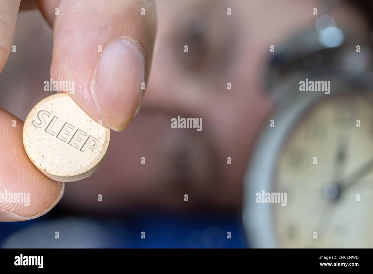 Man lying in bed taking sleeping pill after midnight, close up Stock Photo