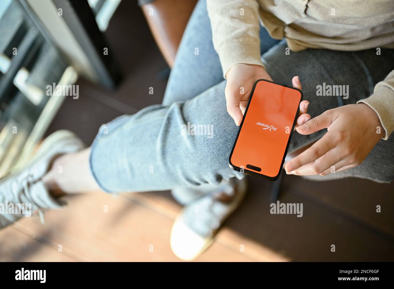 Chiang mai, Thailand - Feb 14 2023: Above view of an Asian woman using Payoneer application on her smartphone. smartphone with PAyoneer logo on screen Stock Photo