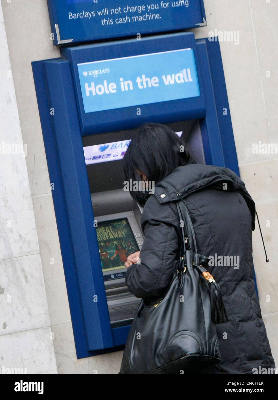 A woman uses an ATM machine in central London, Wednesday, Dec., 29 
