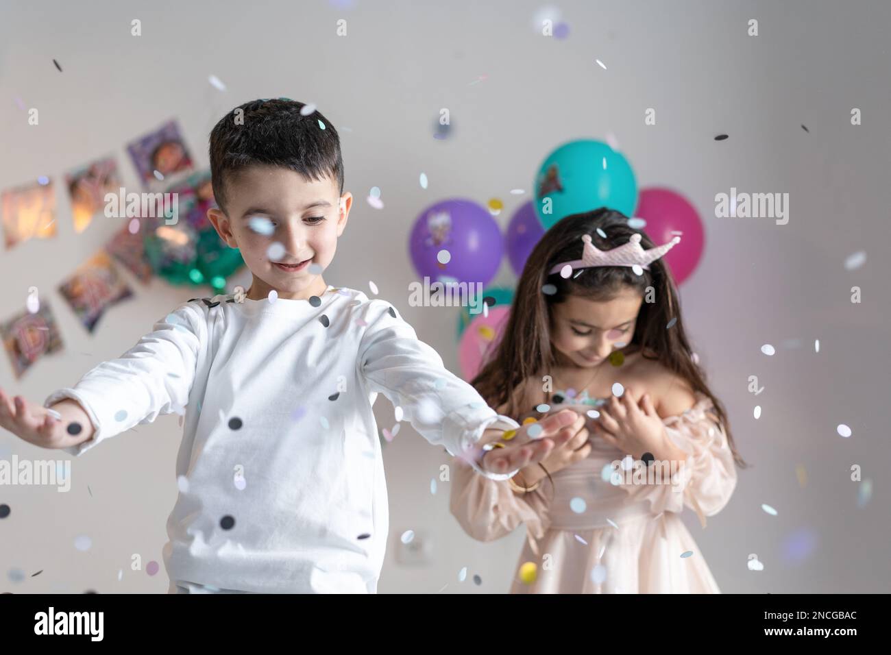 Paper multicolored confetti falling on heads of smiling happy children on birthday party. Stock Photo