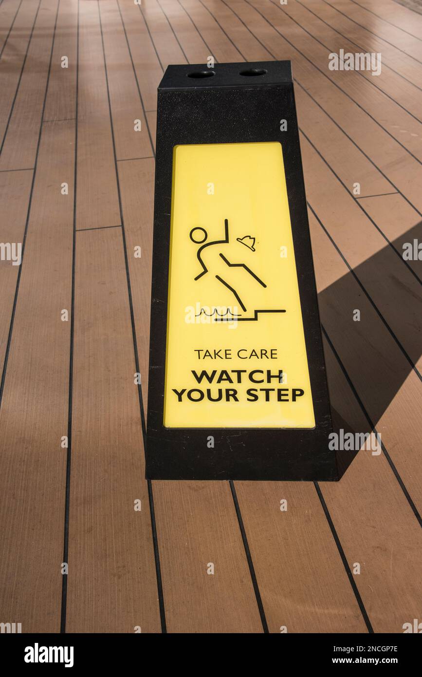 A warning box placed on a deck to warn of potential slippery floor and to use caution. Stock Photo