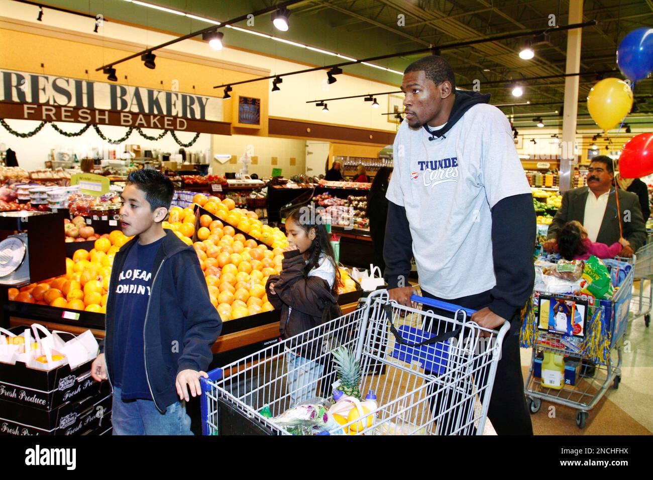 Oklahoma City Thunder s Kevin Durant center leads from left Daniel Gomez and Moniqua Gomez during a shopping spree at a grocery store in Oklahoma City Saturday Dec. 11 2010. Their dad Benjamin