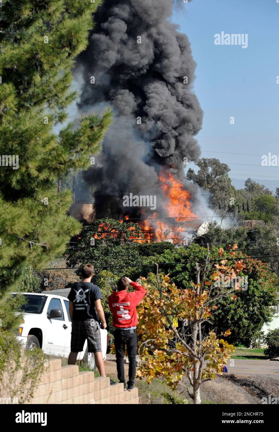Neighbors watch a house enveloped in flames on Thursday, Dec. 9 