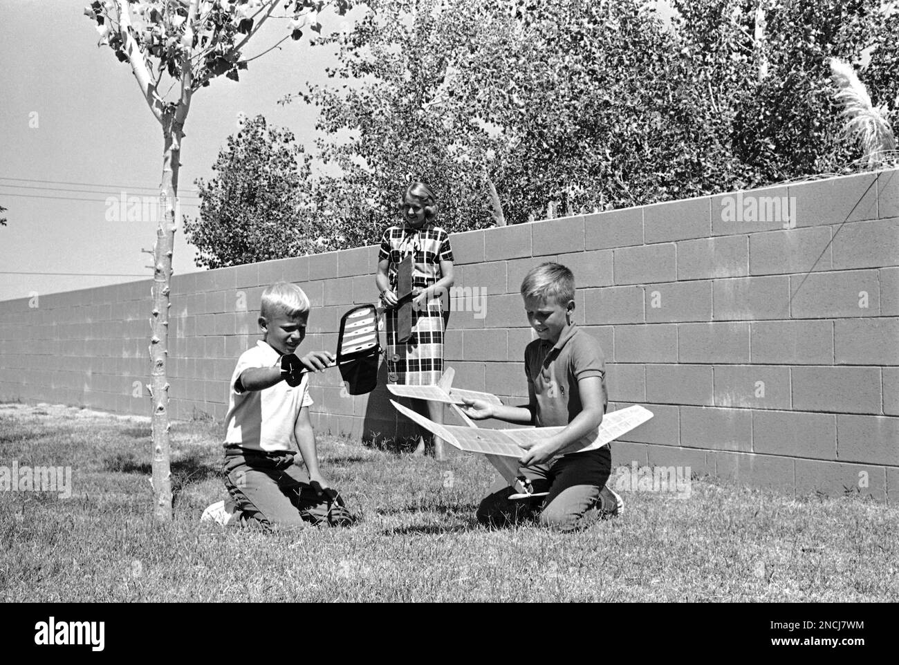 Edwin, left, 9, and Frederick, 11, sons of Air Force Maj. Frank Borman, one  of the nation's new astronauts, play with model airplanes in the backyard  of the Borman home at Edwards