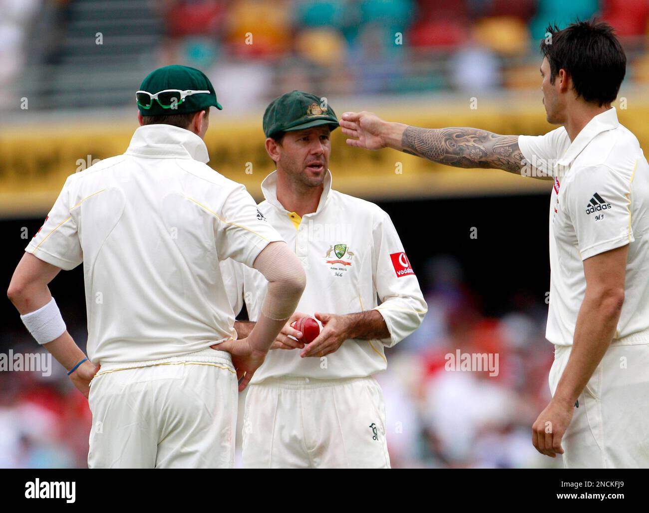 Australia's bnolwers Mitchell Johnson, right, and Peter Siddle, left, talk  with their captain Ricky Ponting during the fourth day of the first Ashes  cricket test against England in Brisbane, Australia, Sunday, Nov.