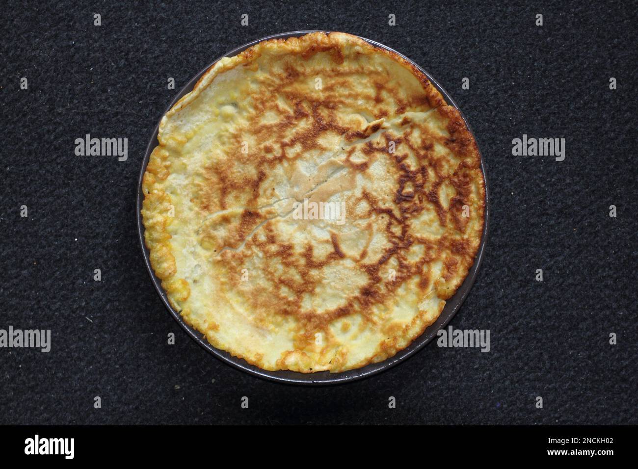 A pancake  is a flat cake, often thin and round, prepared from, a starch-based batter that may contain eggs, milk and butter and cooked on a hot surfa Stock Photo