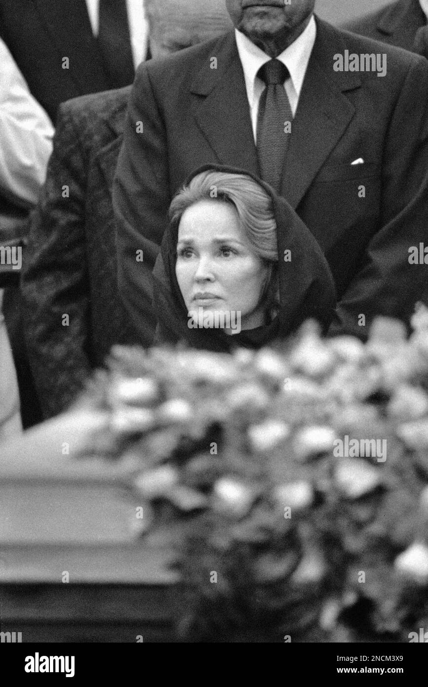Mrs. Kathryn Crosby sits behind the flower laden casket containing her
