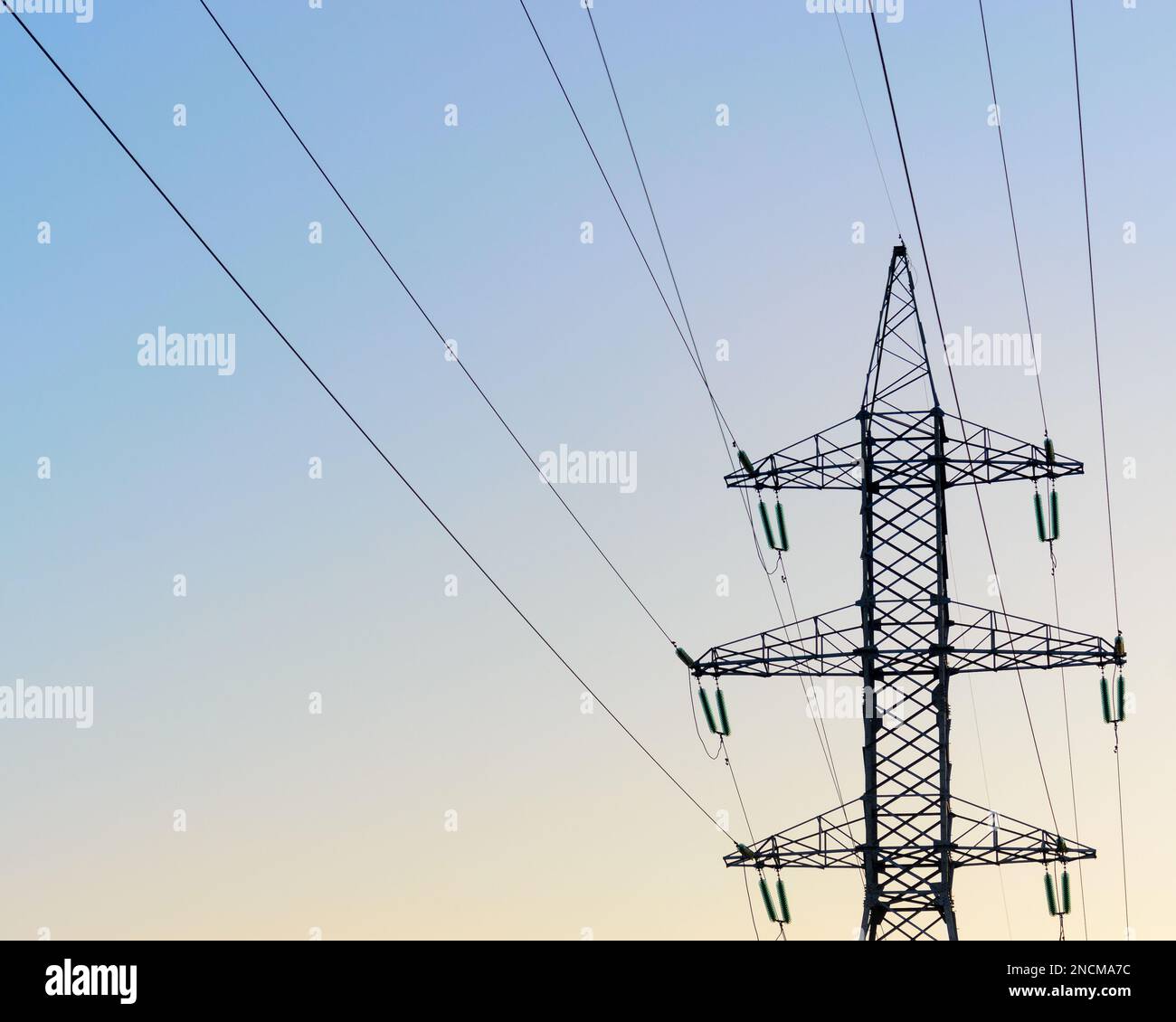 The tip end of the anchor supports of overhead power lines costs with wires and bundles of strands of high-voltage insulators against the clear blue s Stock Photo