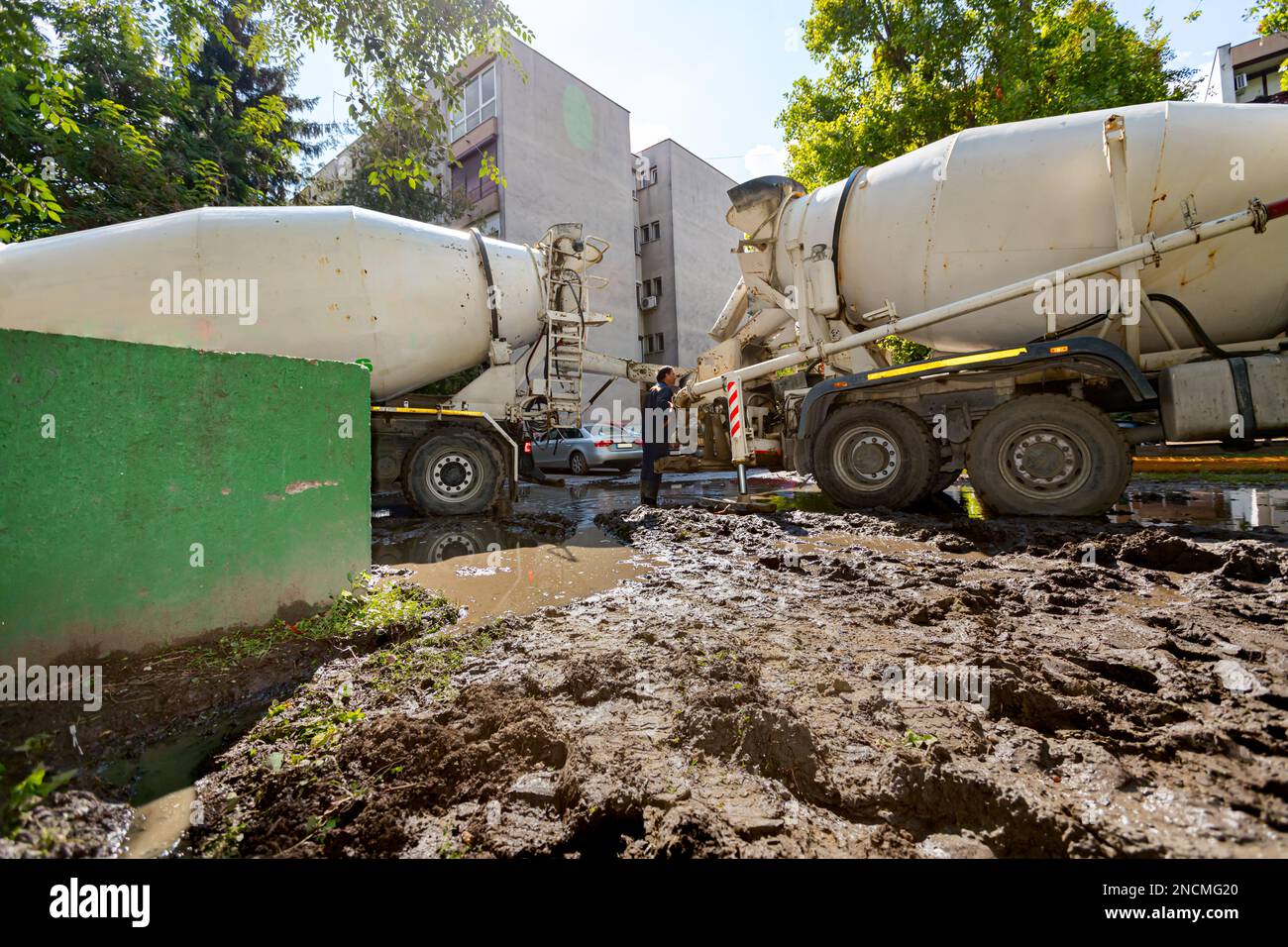 Pouring fresh concrete from mixer truck over ramp to another that has a ...