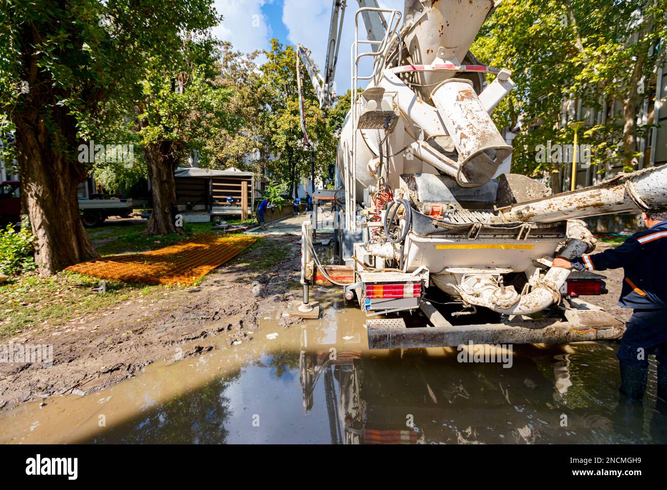 Pouring fresh concrete from mixer truck over ramp to another that has a ...