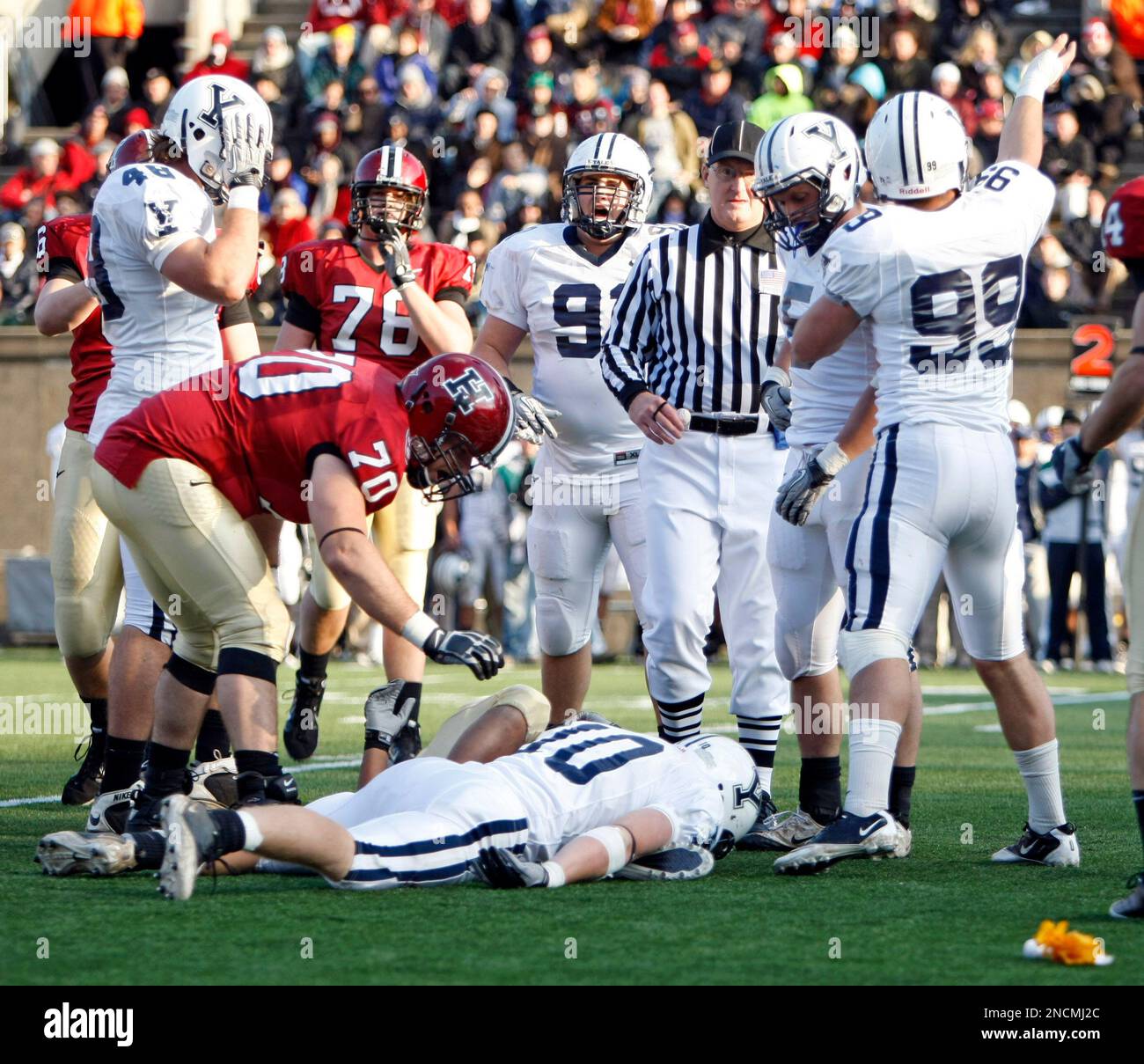 Yale Bulldogs outside line backer Jesse Reising (10) lines on the turf with  Harvard Crimson running back Gino Gordon (22) ,background, moments after  they had a helmet to helmet hit during the
