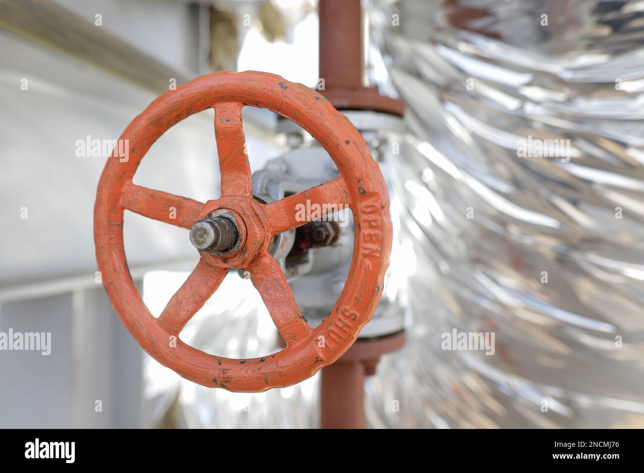 Shallow depth of field details with a metallic pipe valve used to open or close the hot water debit inside a big pipeline. Stock Photo
