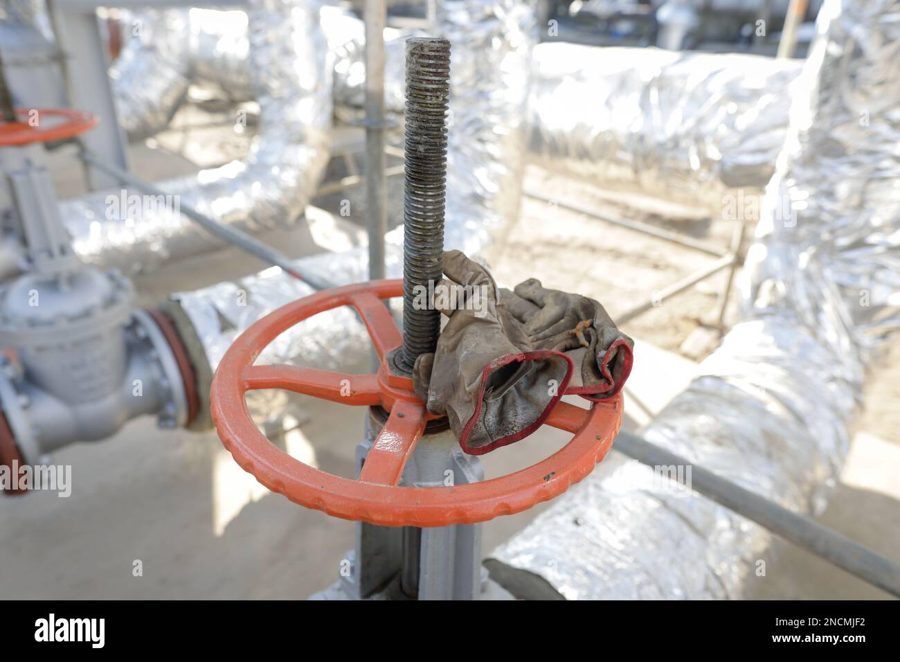 Shallow depth of field details with a metallic pipe valve used to open or close the hot water debit inside a big pipeline. Stock Photo