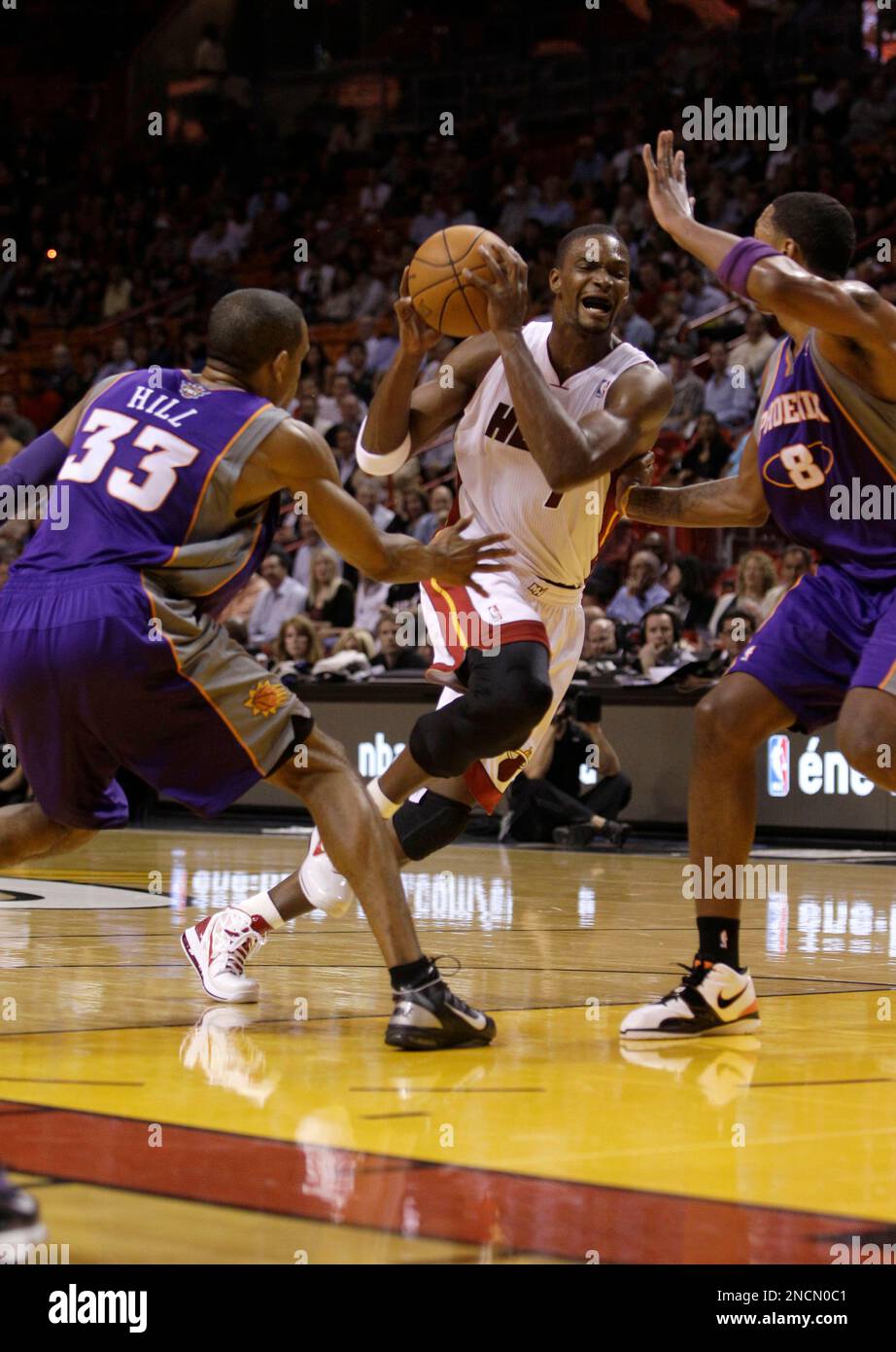 Miami Heat forward Chris Bosh, center, drives to the basket as Phoenix