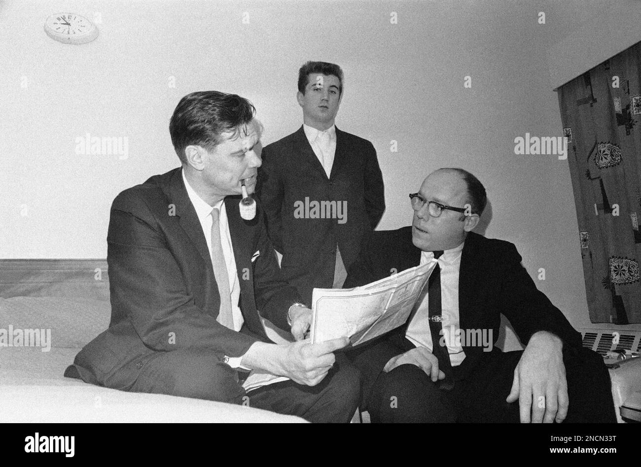 George Lincoln Rockwell, left, of Arlington, Va., and self-appointed “Fuehrer” of the American Nazi Party, discusses plans with his campaign manager Lynn Giesy, right, of Arlington, Va., in a hotel at Concord, New Hampshire, Jan. 25, 1964 for entering the New Hampshire presidential preference primary. Looking on is Storm Leader David Peterson of Minneapolis, Minn. (AP Photo) Stock Photo
