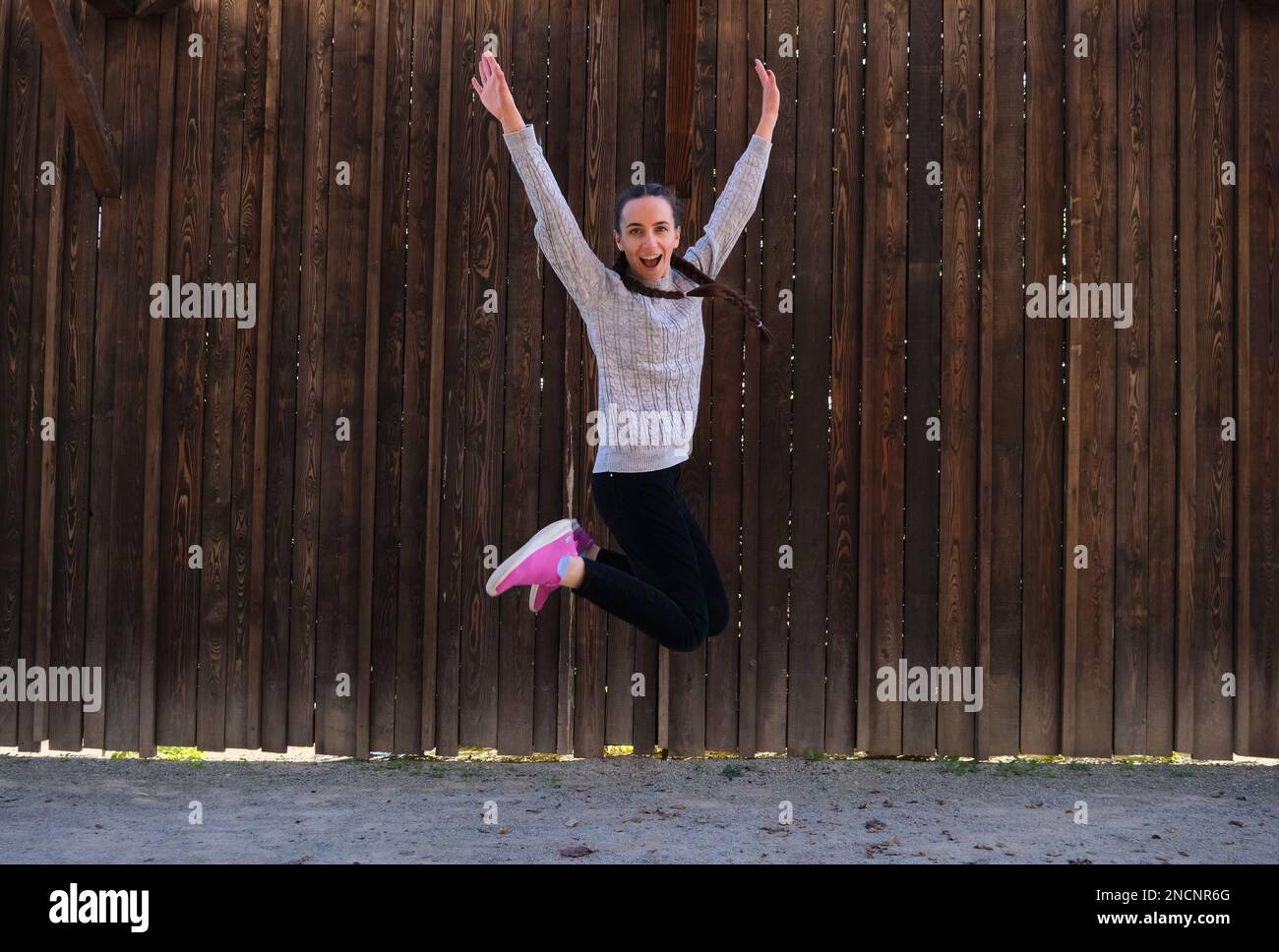 cheerful positive girl jumping in the air with raised hands looking at ...