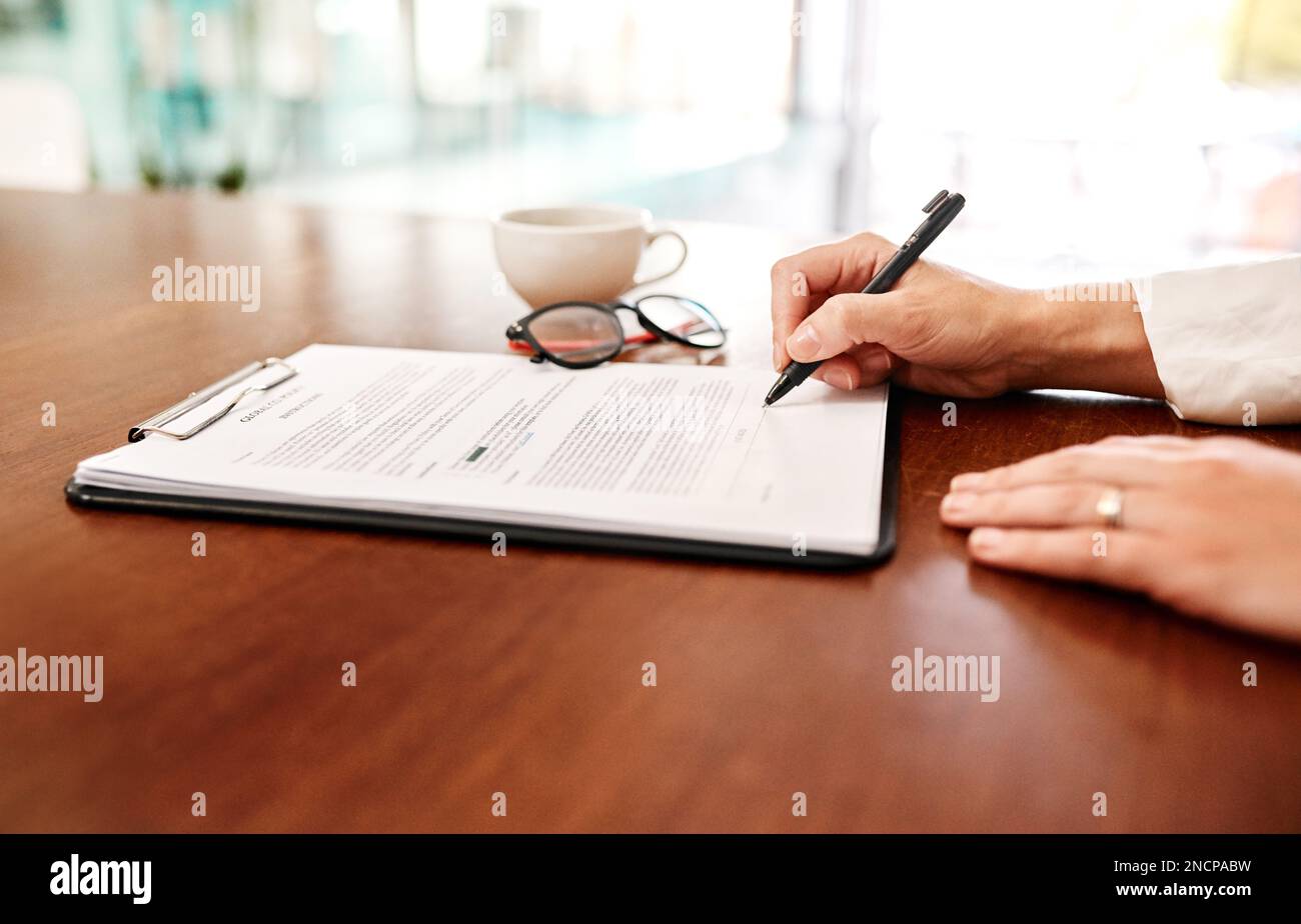 Verifying a new business proposal. Closeup shot of an unrecognisable businesswoman filling in paperwork in an office. Stock Photo