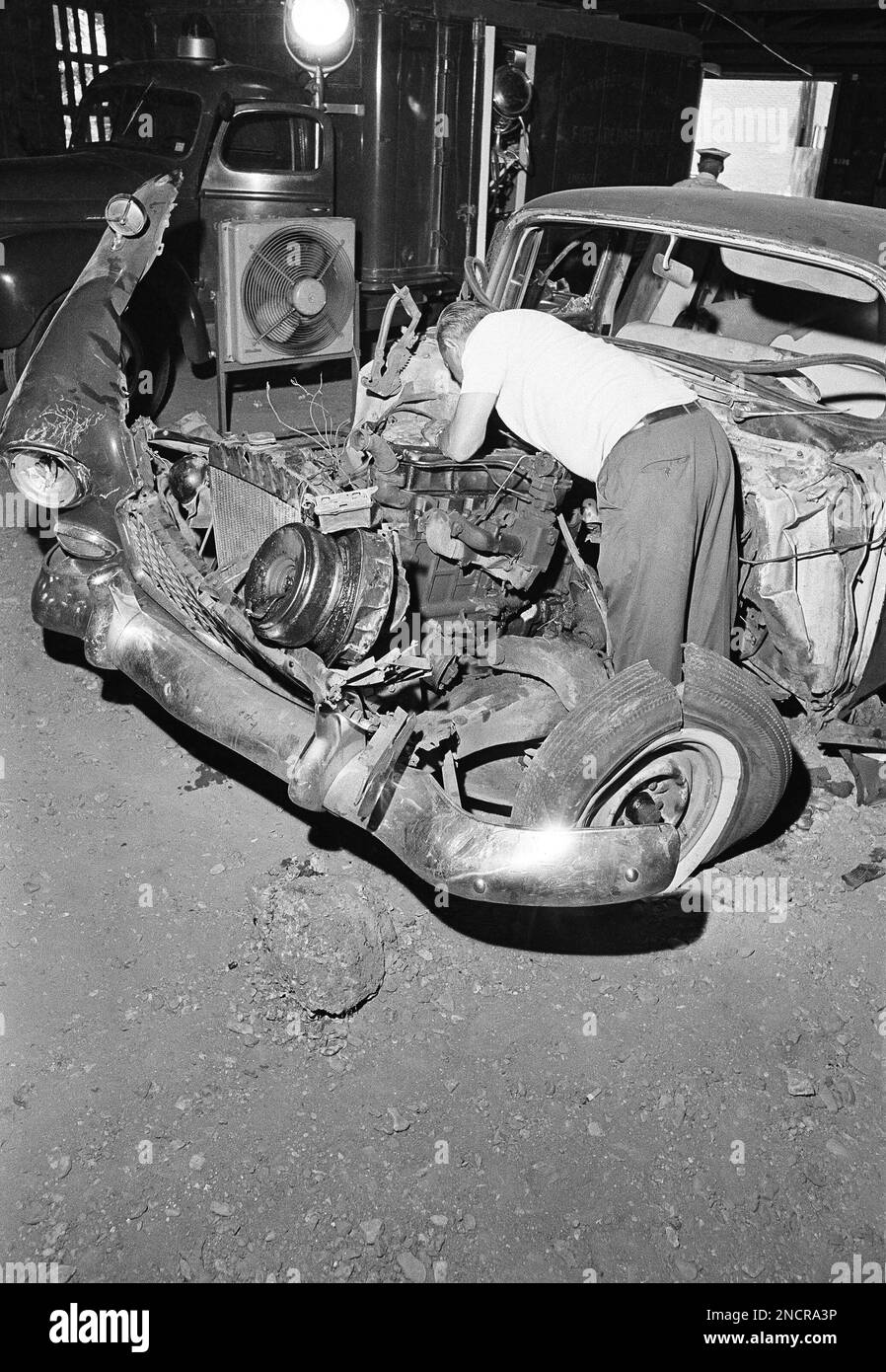 A federal agent of the FBI searches inside the damaged car of a civil