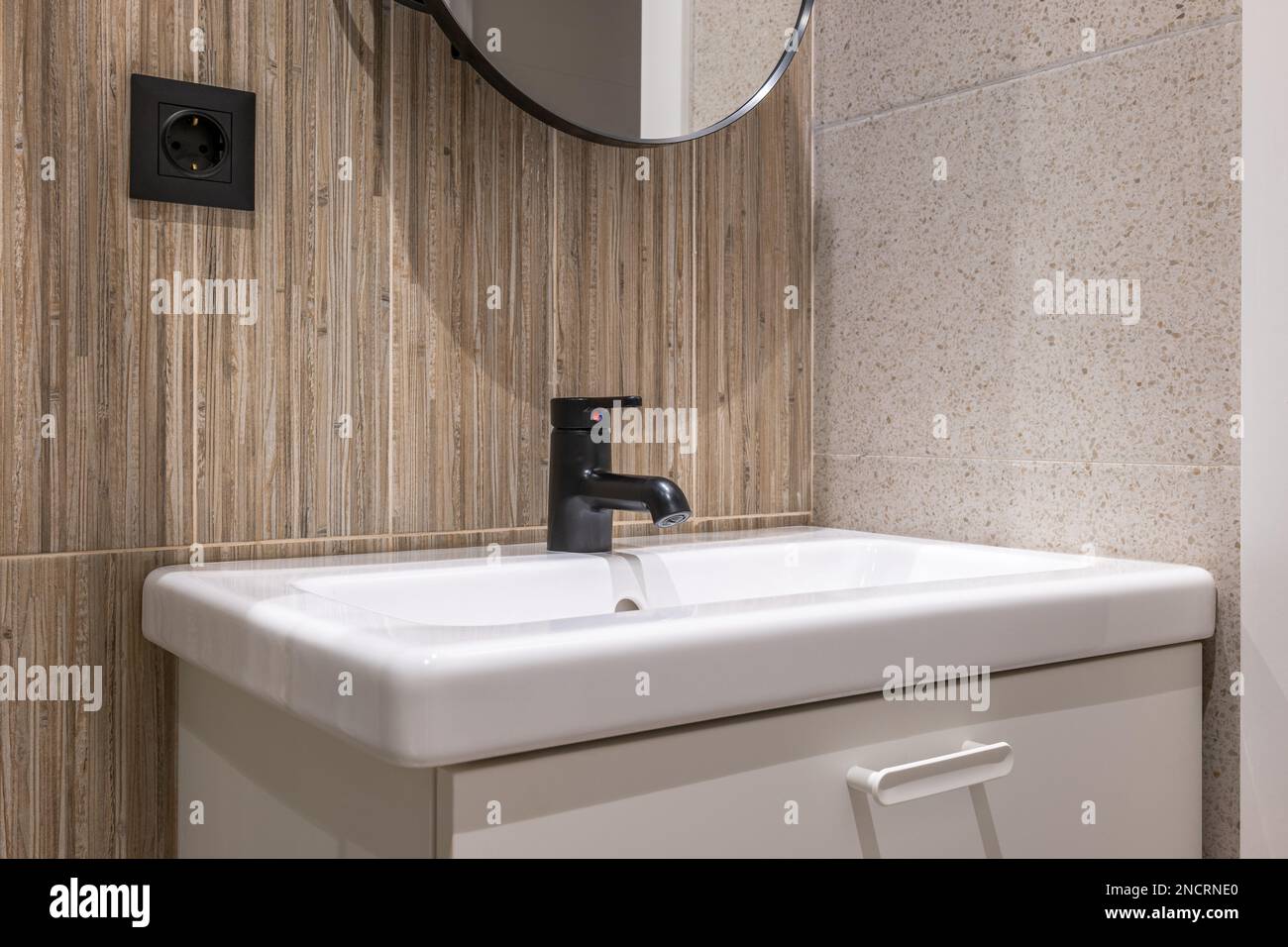 Bathroom sink on vanity is illuminated by bright light from ceiling. Walls are combination of