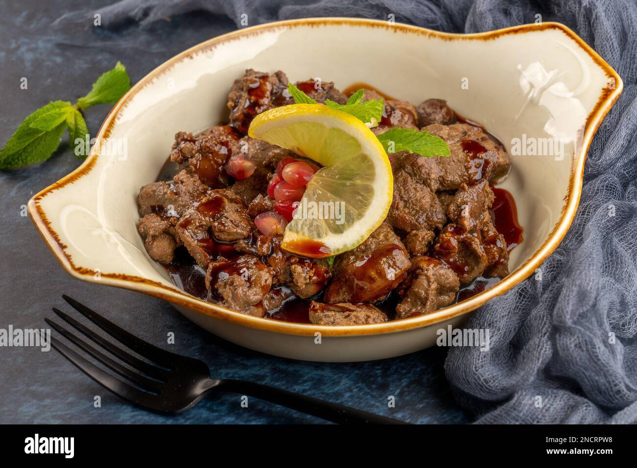 A closeup shot of chicken leaver served with sauce and lemon, hot appetizer Stock Photo