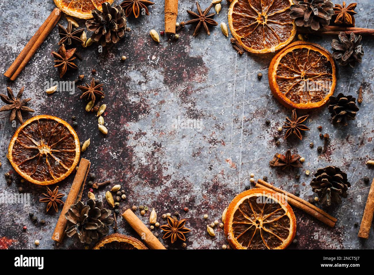 Cinnamon, cloves, pepper, dried oranges anise grey background. Frame