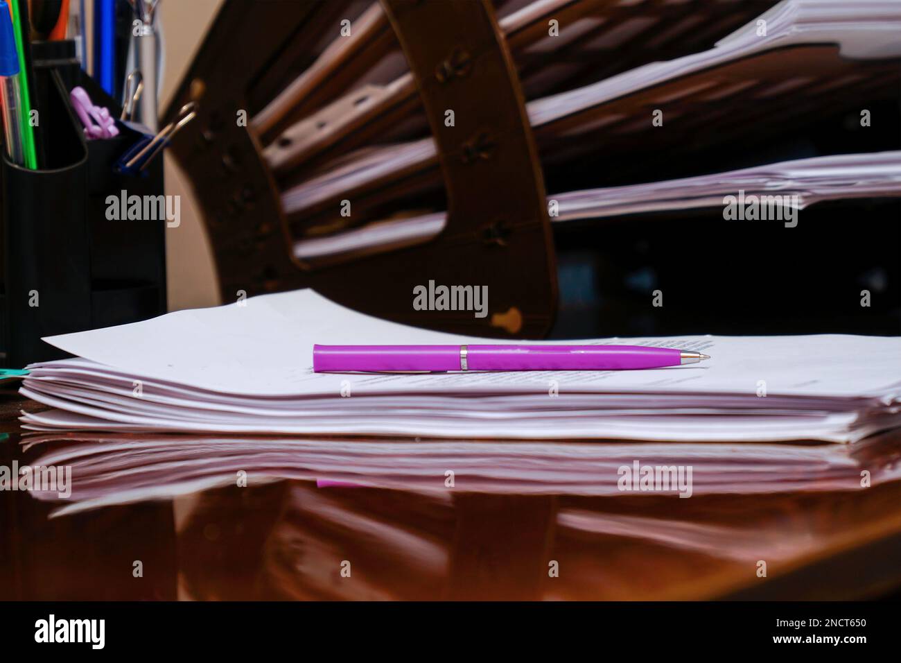 Plastic organizer for documents on the office desk. The pink pen lies on business papers, documents Stock Photo