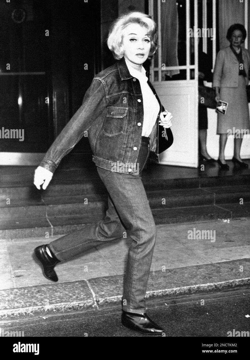 Wearing a Blue denim jacket and trousers, movie star Marlene Dietrich walks  from her London Hotel, Oct. 25, 1963. The German-Born actress was in route  to a rehearsal for the "Alamein" Reunion