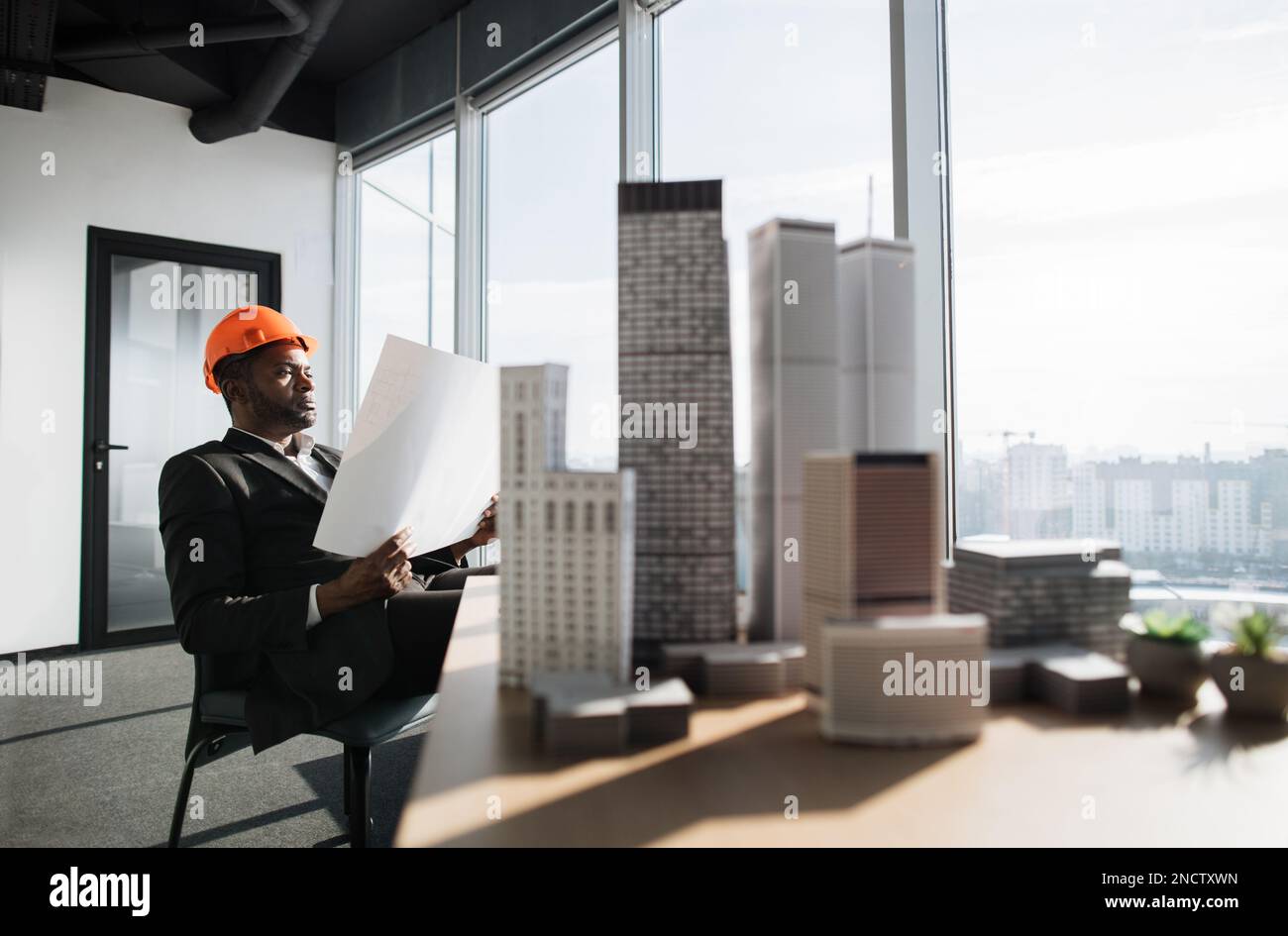 Office interior with panoramic city view. Handsome chief architect man ...