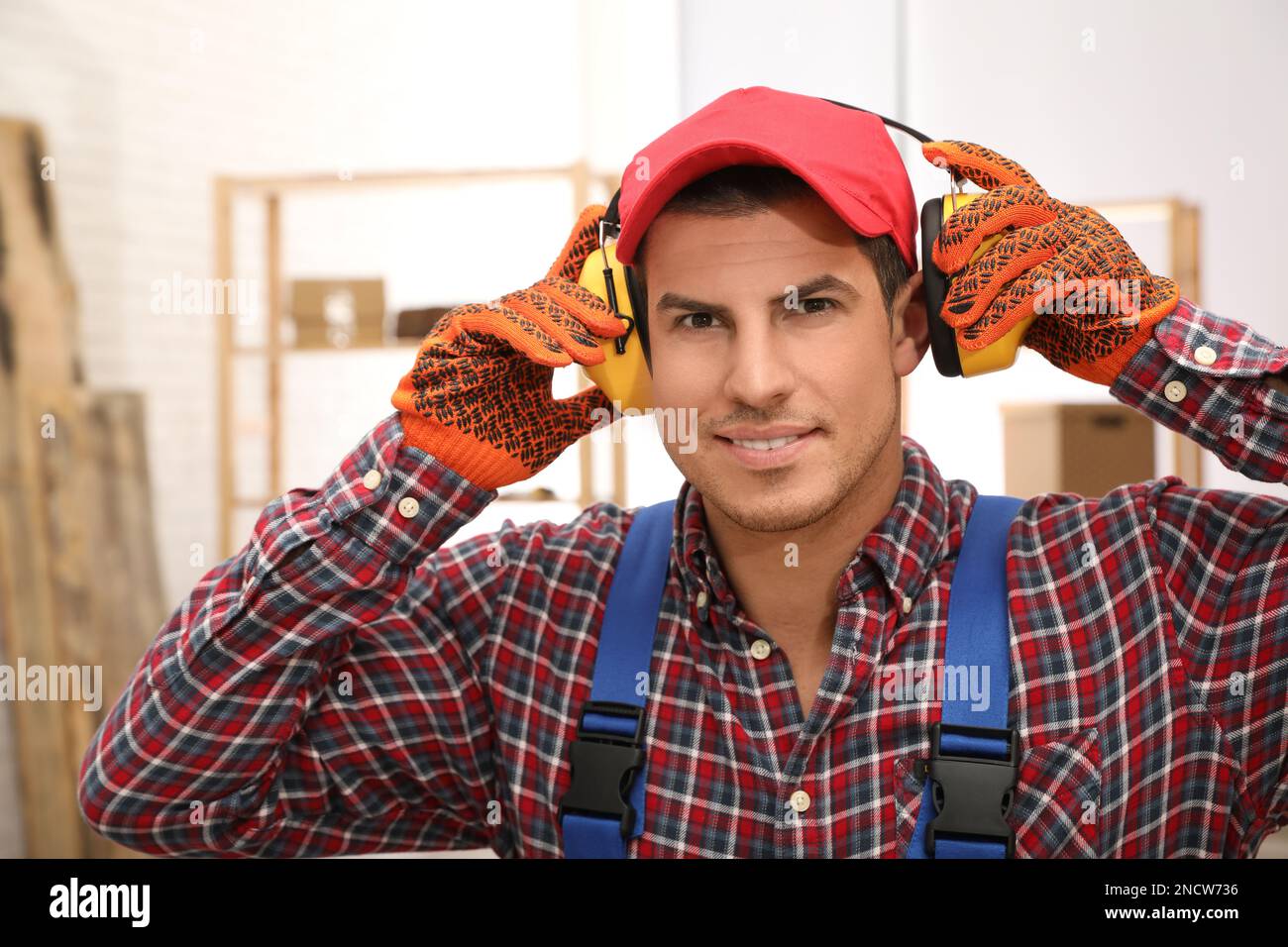 Worker wearing safety headphones indoors. Hearing protection device